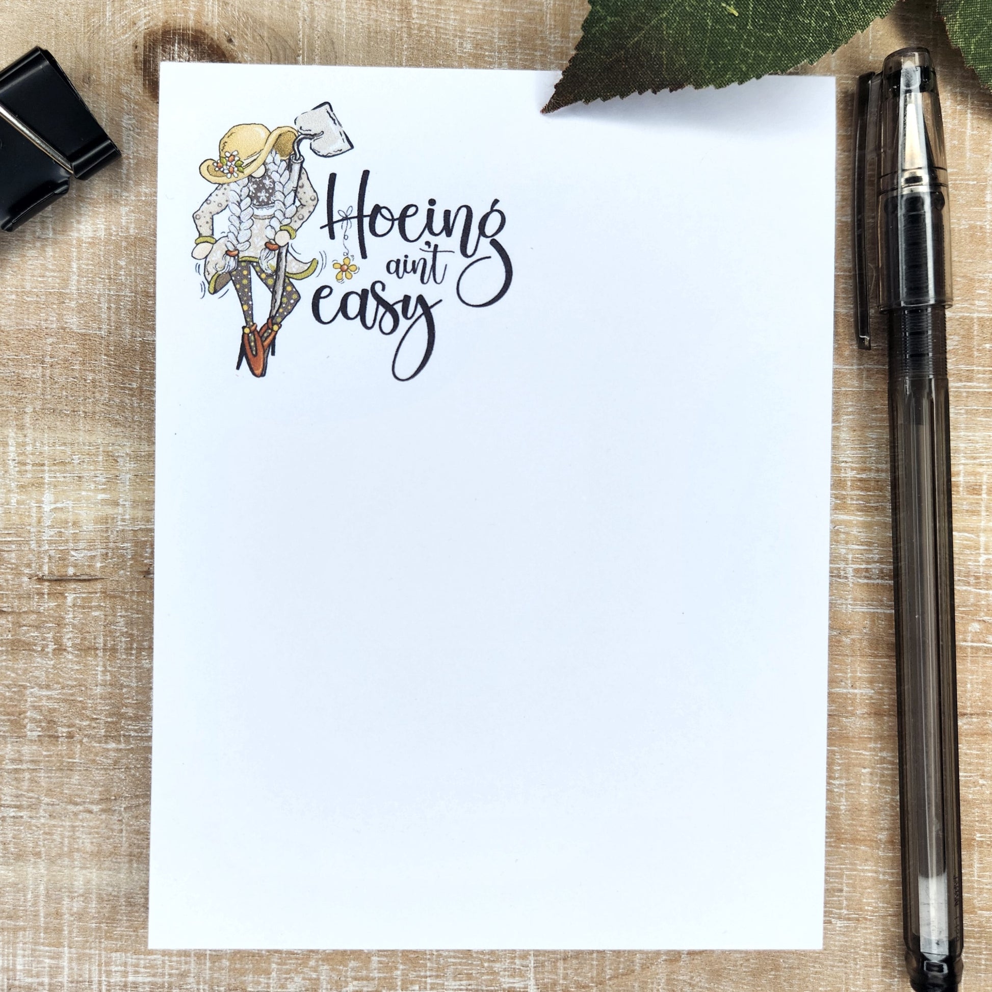 girl gnome in braids, floppy hat, and heals. She is holding a garden hoe. Words 'Hoeing Ain't Easy" accompany the pictures