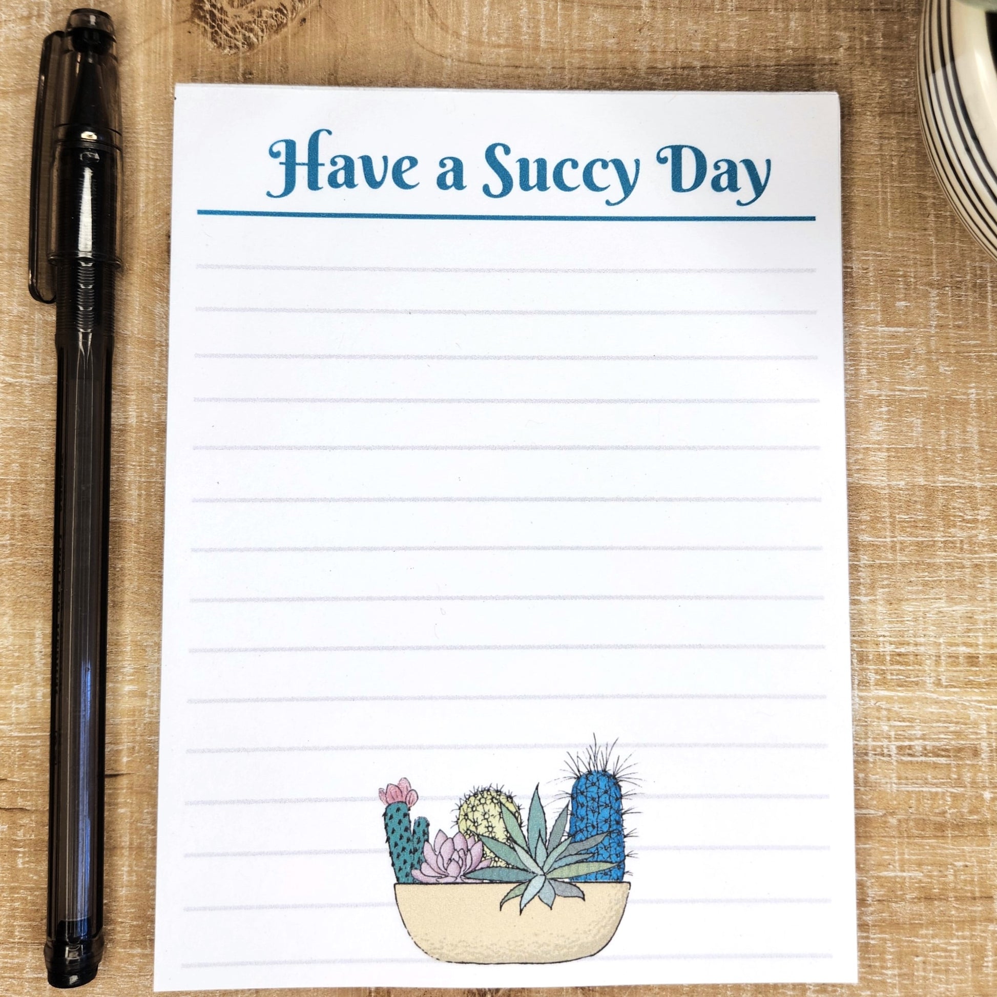 Have a Succy Day notepad is on a tan background. notepad has lines and a bowl of succulents on the bottom.